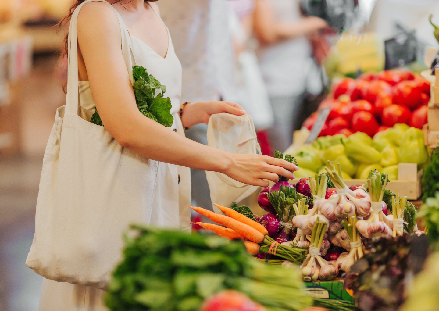 Photo d'une femme touchant les fruits et légumes sur l'étal dans un marché - © M ton Marché Photo d'une femme touchant les fruits et légumes sur l'étal dans un marché