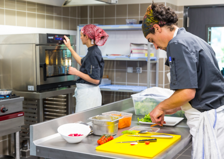 Deux commis travaillent dans les cuisines d'un restaurant